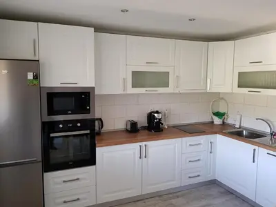 a white kitchen with white cabinets and black appliances at United Apartments 2 in Sandanski