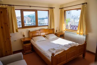 a bedroom with a wooden bed and two windows at Pri Ani Guest House in Bansko