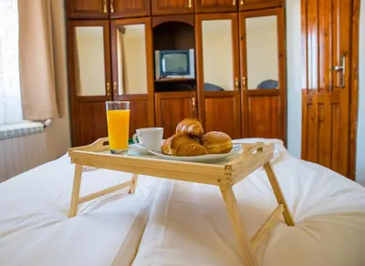 a tray with bread and a glass of orange juice on a bed at Pri Ani Guest House in Bansko