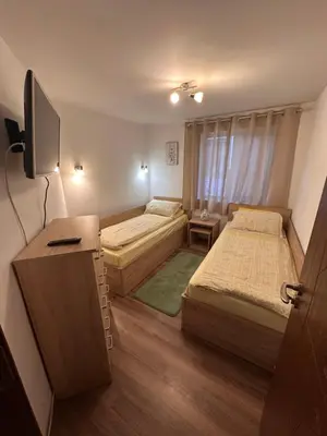 a small room with two beds and a television at Къща за гости Romano in Chepelare