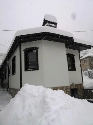 a snow covered house with a pile of snow at Къща за гости Romano in Chepelare