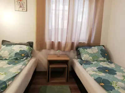 a pair of beds in a room with a table at Къща за гости Romano in Chepelare