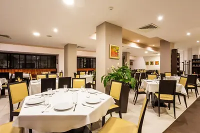 a restaurant with white tables and yellow chairs at Hotel Perun Lodge in Bansko