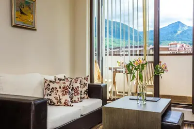 a living room with a couch and a table with flowers at Hotel Perun Lodge in Bansko