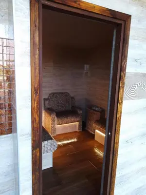 a glass door into a living room with a chair at A-Apartment in Krasnovo