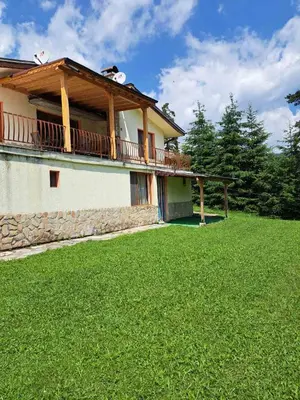a house with a balcony and a grass yard at Vila Katerina in Yundola