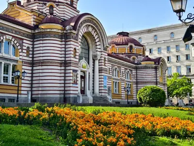 a large building with flowers in front of it at Apartment Audrey by SofiaSpot - central, metro to airport in Sofia