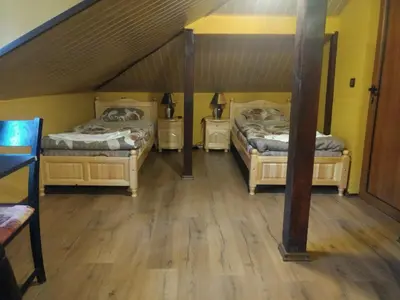 two beds in a room with wooden floors at Къща за гости с минерална вода 
