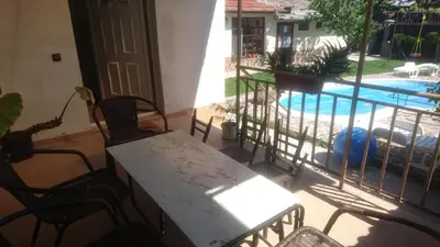 a patio with a table and chairs and a swimming pool at Къща за гости с минерална вода 