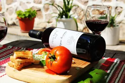 a bottle of wine and a glass of red wine and tomatoes at Hotel Slavova Krepost in Melnik