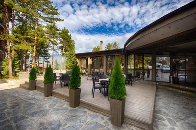 a restaurant with tables and chairs on a deck at Hotel Panorama Velingrad in Velingrad