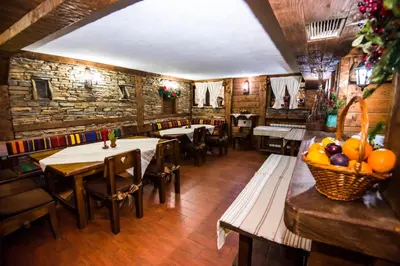 a restaurant with tables and chairs and a stone wall at Elida Family Hotel in Bansko