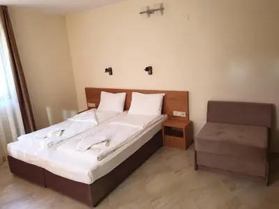 a bedroom with a large bed and a chair at хотел Чифлика - комплекс Чифлика in Chiflik
