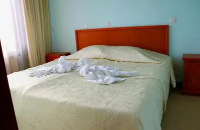 a bed with white sheets and towels on it at Family Hotel LILI in Bansko