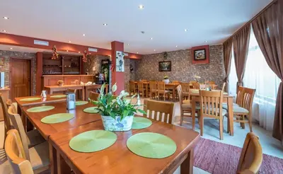 a dining room with a large wooden table and chairs at Family Hotel LILI in Bansko