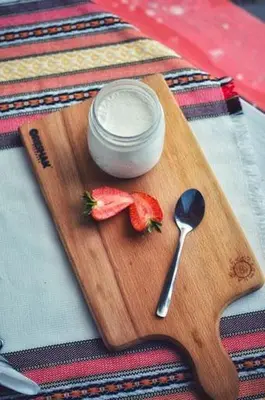 a wooden cutting board with a spoon and a jar of cream at Zlatna ribka in Kokolyane