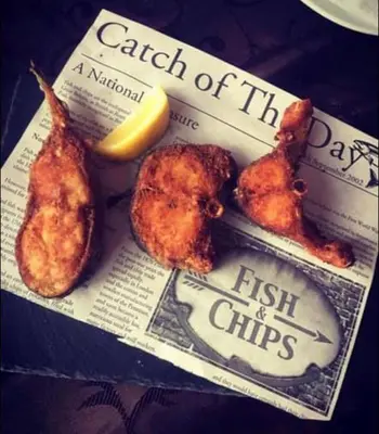 a newspaper with chicken wings and a lemon on it at Zlatna ribka in Kokolyane