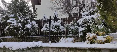 a fence covered in snow in front of a house at Guest House Ela in Bansko