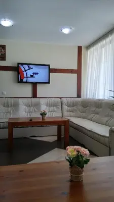 a living room with a couch and a flat screen tv at Guest House Ela in Bansko
