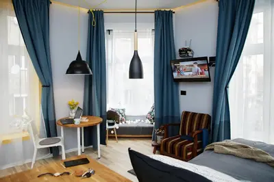 a bedroom with blue curtains and a table and a bed at Courthouse Apartments Slavi in Sofia