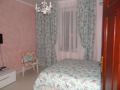a bedroom with a bed and curtains and a chair at Orange Flower Apartments in Sofia