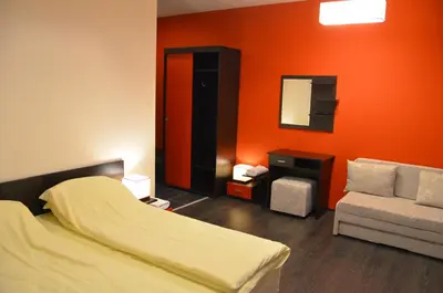 a bedroom with an orange wall and a bed and a couch at Villa Galiana in Simitli