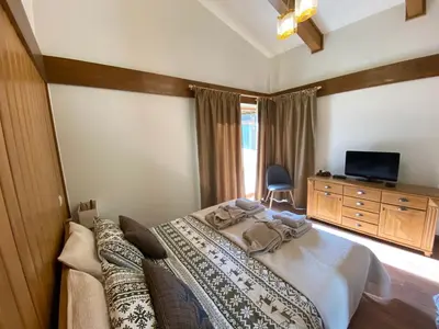 a bedroom with a bed and a dresser and a television at Pirin Golf and Spa Luxury Chalet in Bansko