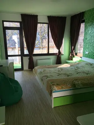 a bedroom with a large bed and two windows at Къща за гости Суни Транс in Smolyan