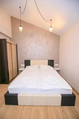 a bedroom with a large white bed with two lights at Апартаменти Принц и Принцеса in Sandanski