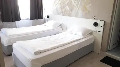 two beds in a room with white sheets and pillows at Rio Family Hotel in Blagoevgrad