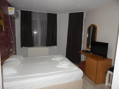 a bedroom with a white bed and a television at Rio Family Hotel in Blagoevgrad