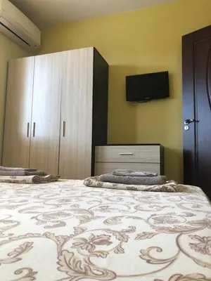 a bedroom with two beds and a tv on the wall at Апартамент ТЕА in Sandanski