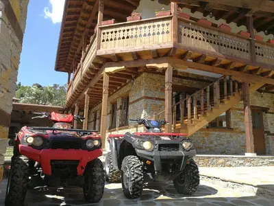 two atvs parked next to a building with a balcony at Слънчевата къща in Kovachevitsa