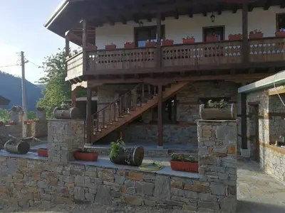 a building with a balcony with plants in pots at Слънчевата къща in Kovachevitsa