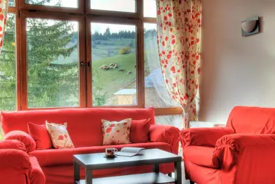 a living room with red couches and a large window at The Poppies House in Pamporovo