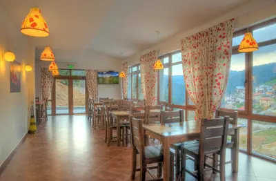 a dining room with tables and chairs and windows at The Poppies House in Pamporovo