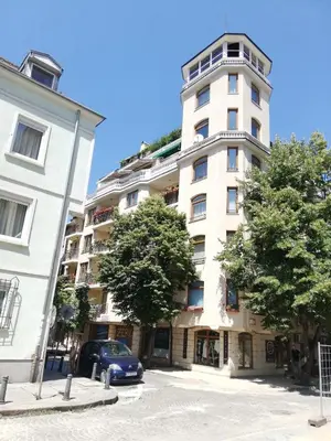 a tall white building with a car parked in front of it at Apartment Button in downtown in Sofia