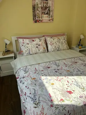 a bedroom with a bed with a floral comforter and pillows at Roma Apartment in Sandanski