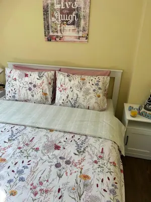 a bedroom with a bed with a floral bedspread and pillows at Roma Apartment in Sandanski