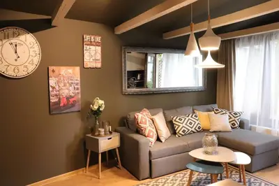 a living room with a couch and a clock on the wall at Urban House in Sofia