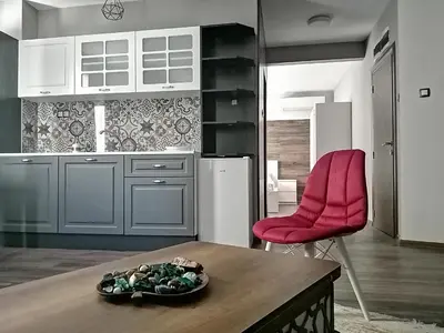 a kitchen with a table and a red chair at The old Bakery Apartments in Plovdiv