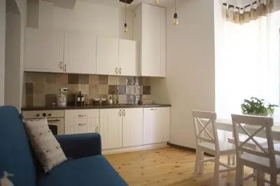 a kitchen with white cabinets and a blue couch at The FlyingTheatre Suites in Plovdiv