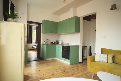 a kitchen with green cabinets and a living room at The FlyingTheatre Suites in Plovdiv