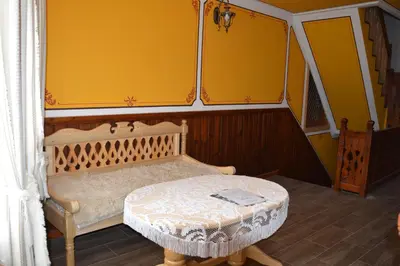a yellow room with a bed and a table at Стаи за гости Дончо Войвода in Koprivshtitsa
