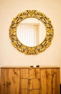 a gold mirror on a wall above a wooden dresser at Sofia Crown Life Apartment in Sofia