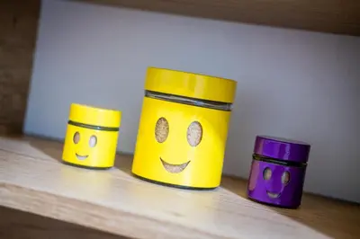 three yellow cups with faces on them sitting on a shelf at Sofia Colour Life Apartment -No Window Apartment in Sofia