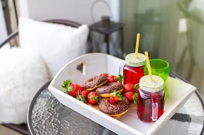 a tray of donuts and strawberries on a table at Domus Apartments Grand with Parking in Plovdiv