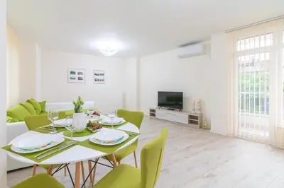 a dining room with a table and green chairs at Domus Apartments Grand with Parking in Plovdiv