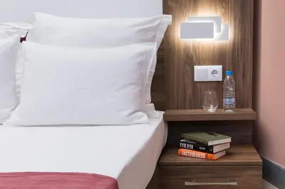 a hotel room with a bed and a night stand with books at B1 Boutique Hotel Sofia in Sofia