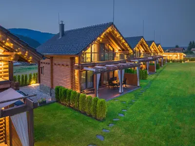 a row of wooden lodges on a lawn at night at Samovilla in Govedartsi
